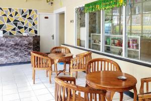 ein Restaurant mit Holztischen und -stühlen und einer Theke in der Unterkunft RedDoorz Syariah Near Pelabuhan Sri Bintan Pura Tanjungpinang in Tanjung Pinang 