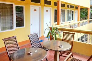twee tafels en twee stoelen op een veranda met een huis bij RedDoorz Syariah Near Pelabuhan Sri Bintan Pura Tanjungpinang in Tanjung Pinang 