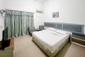 a bedroom with a large white bed and a chair at RedDoorz Syariah Near Pelabuhan Sri Bintan Pura Tanjungpinang in Tanjung Pinang 