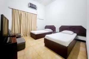una camera d'albergo con due letti e una televisione di RedDoorz Syariah Near Pelabuhan Sri Bintan Pura Tanjungpinang a Tanjung Pinang