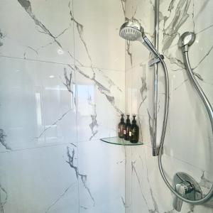 奥克兰Wheturangi Urban Escape的带淋浴的浴室,在架子上装有葡萄酒瓶