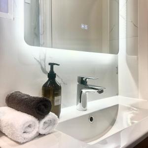 a bathroom sink with a bottle of soap and a mirror at Wheturangi Urban Escape in Auckland