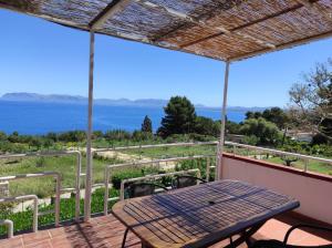 a table on a deck with a view of the ocean at Bellavista Apartments in Scopello