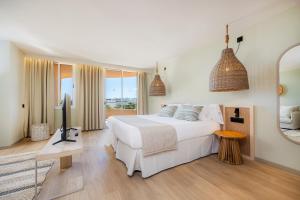 a white bedroom with a large bed and a television at Marins Beach Club - Adults Only Hotel in Cala Millor