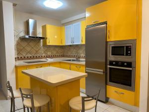 a kitchen with yellow cabinets and a counter with chairs at Vivienda Vacacional VillaVerde in Valverde