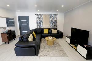 a living room with a black leather couch and a tv at Casa da Calheta in Maia
