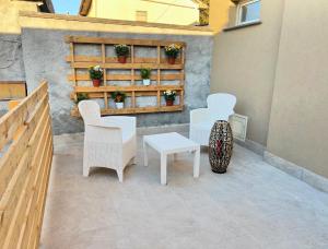 un patio con sillas blancas, una mesa y un banco en Easy Room en Catania