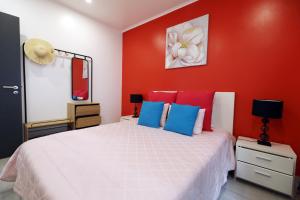 una camera con un letto bianco e pareti rosse di Casa da Calheta a Maia