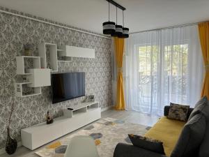 a living room with a tv on a wall at White DeLuxe Apartment in Ploieşti