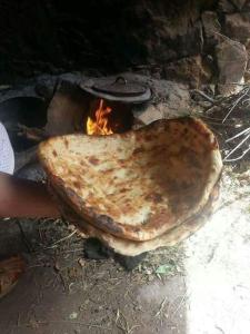 uma pessoa segurando um pedaço de pão em frente a uma fogueira em Ouadaker amizmiz em Amizmiz