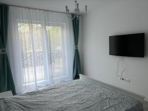 a bedroom with a bed and a television on a wall at White DeLuxe Apartment in Ploieşti