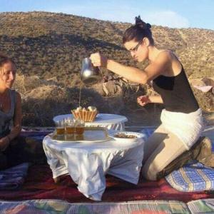 Ouadaker amizmiz في أمزميز: امرأة تقف بجوار طاولة مع غلاية الشاي