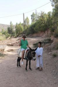 uma mulher e uma criança num burro numa estrada de terra em Ouadaker amizmiz em Amizmiz