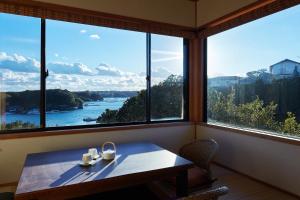 a table in a room with a view of the water at Villa Ryusei in Ugata