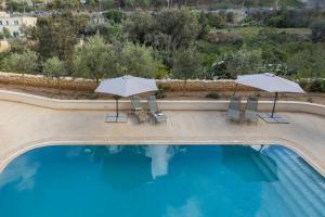 圣朱利安斯Mensija Valley Suites and Apartments的一个带两把遮阳伞和两把椅子的游泳池和一个游泳池 更多63张照片