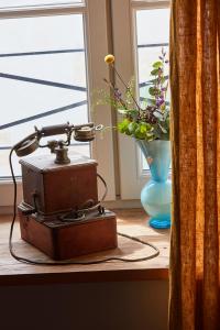 an old sewing machine on a table with a vase of flowers at Maisons 322 - La Flamboyante in Le Bois-Plage-en-Ré