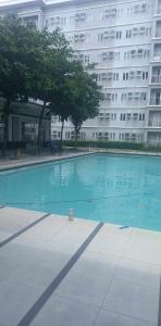 a large swimming pool in front of a large building at Comfy 1 Bedroom with Netflix & Free Wifi - Trees Residences Condominium in Manila