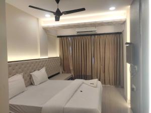 een slaapkamer met een wit bed en een plafondventilator bij OYO Flagship HOTEL MAIREAD in Umele