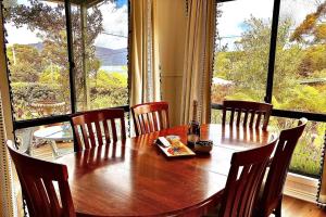 mesa de comedor con sillas y ventana grande en Bruny Serenade, en Adventure Bay