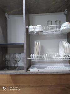 a kitchen shelf with plates and wine glasses on it at Новая 1 комнатная квартира в мкр Аэропорт in Kostanay