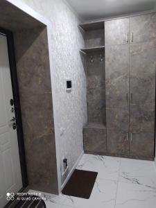 y baño con ducha y pared de piedra. en Новая 1 комнатная квартира в мкр Аэропорт en Kostanái