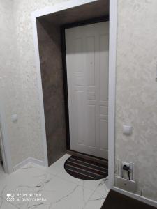 Una puerta blanca con una alfombra delante. en Новая 1 комнатная квартира в мкр Аэропорт en Kostanái