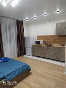 a room with a kitchen and a bed and a counter at Новая 1 комнатная квартира в мкр Аэропорт in Kostanay