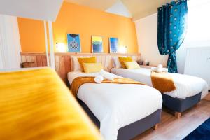 two beds in a room with yellow walls and blue curtains at Lets Relax - Coté Soleil Levant in Mons
