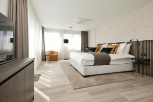 una camera da letto con un grande letto bianco e una televisione di Boutique Hotel Hans a Badhoevedorp