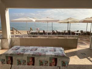 een patio met tafels en parasols op het strand bij Broadway es Mar in El Perelló