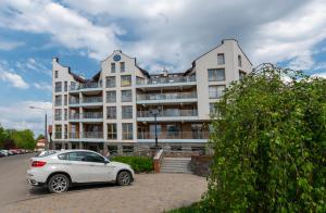 un coche blanco estacionado frente a un edificio en Ełcka Bryza, en Ełk