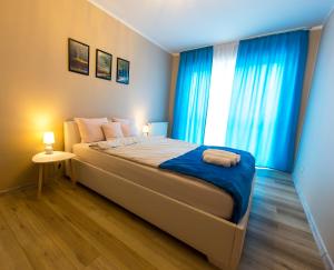 1 dormitorio con 1 cama grande y cortinas azules en Ełcka Bryza en Ełk