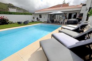 a swimming pool with lounge chairs next to a house at Casa da Calheta in Maia