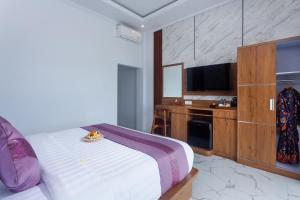 a hotel room with a bed and a flat screen tv at Samuh Sunset Nusa Penida by Pramana Villas in Nusa Penida