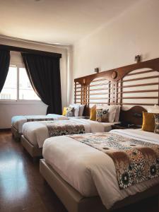 um quarto de hotel com três camas e uma janela em Hôtel Rembrandt em Tânger