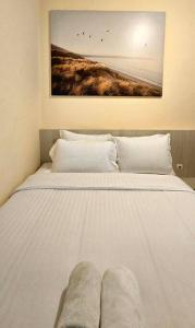 ein weißes Bett mit zwei Kissen und einem Gemälde an der Wand in der Unterkunft Typo House at Royal Residence in Surabaya