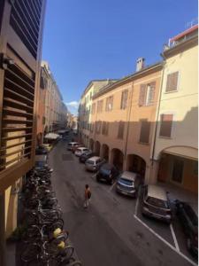 Un uomo che cammina per una strada con una fila di macchine parcheggiate di Casa Rella - Camera Rose a Bologna