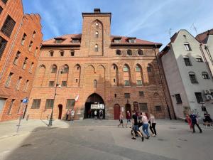 un groupe de personnes marchant devant un grand bâtiment en briques dans l'établissement H&T Old Town Szeroka 36, à Gdańsk