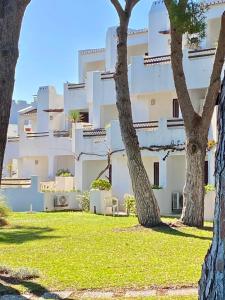 ein großes weißes Gebäude mit Bäumen im Vordergrund in der Unterkunft Balaia Golf Village in Albufeira