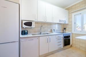 una cucina con armadi bianchi, lavandino e forno a microonde di Apartamento Minerva a Alcudia