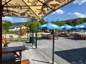 un gruppo di tavoli con ombrelloni blu e parco giochi di JAMY HOUSE Apartmán a Habovka