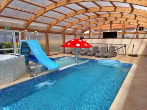 a indoor pool with a slide and an umbrella at Zefir SPA in Polańczyk