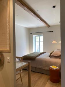 a bedroom with a bed and a table and a window at Mas provençal d'exception in La Garde-Adhémar