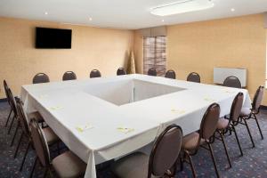 una sala conferenze con tavolo e sedie bianchi di Days Inn by Wyndham Brantford a Brantford
