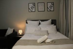 Una cama con sábanas blancas y almohadas en un dormitorio en Cozy Studio in Midrand en Midrand