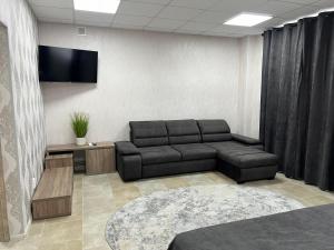 Motel Xameleon في Voznesensk: غرفة معيشة مع أريكة وتلفزيون بشاشة مسطحة