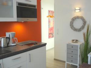 una cocina con armarios blancos y una pared de color naranja en Hermer Suite 3, en Grömitz