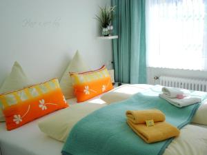 1 dormitorio con 2 camas con almohadas de color naranja y azul en Hermer Suite 3, en Grömitz