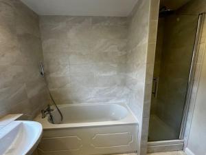 y baño con bañera, lavamanos y ducha. en Fantastic house, great location en Laindon