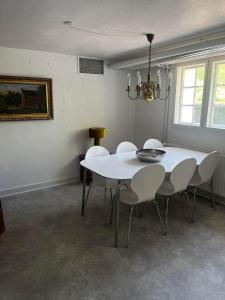 une salle à manger avec une table et des chaises blanches dans l'établissement Rosenlund Gods - kælder B&B, à Sakskøbing